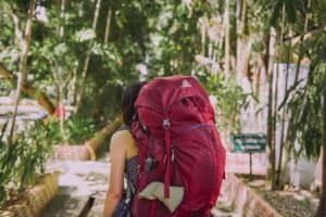 Rucksackreisen - Frau mit rotem Rucksack