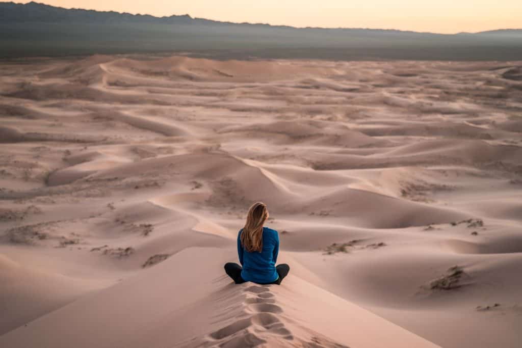 Frau sitzt im Wüstensand