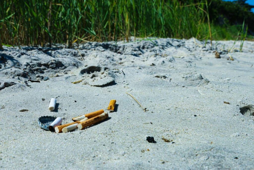 Zigaretten und Kronkorken als Müll am Strand
